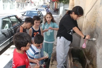 Sıcak havadan bunalan çocuklar su savaşı yaparak serinlediler
